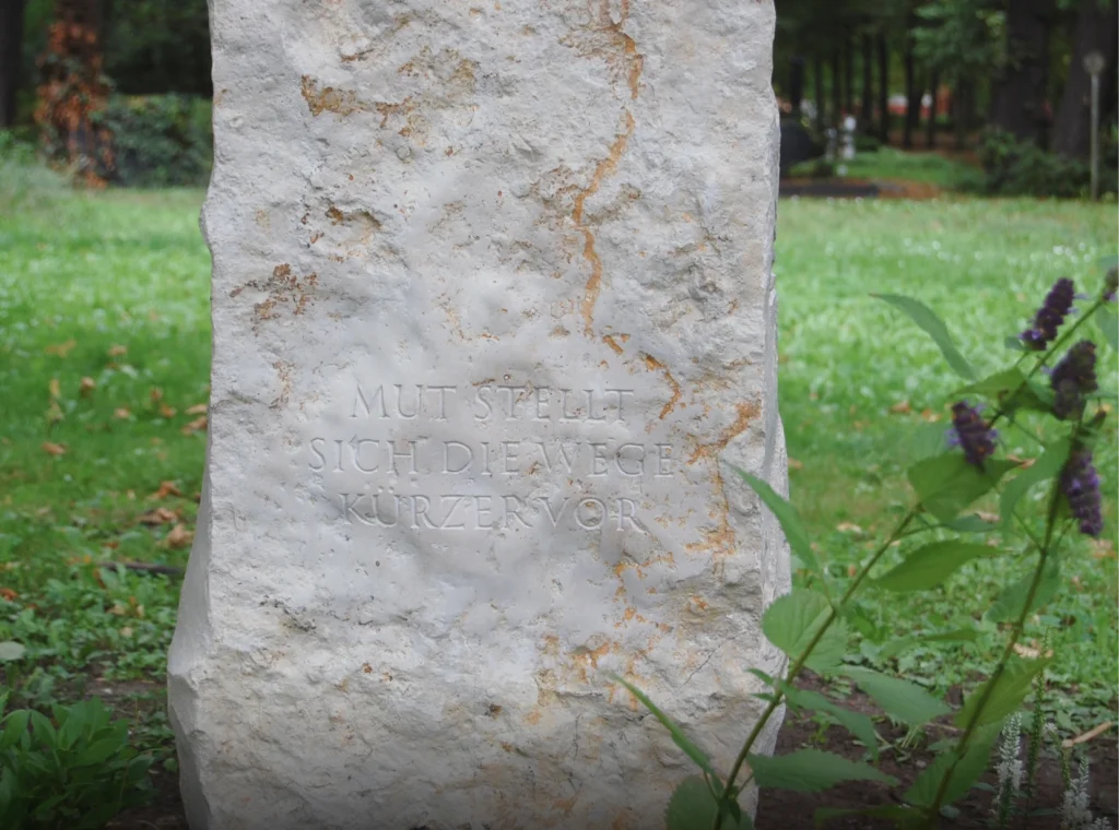 Detail eines Grabsteins mit eingraviertem Schriftzug „Mut stellt sich die Wege kürzer vor“