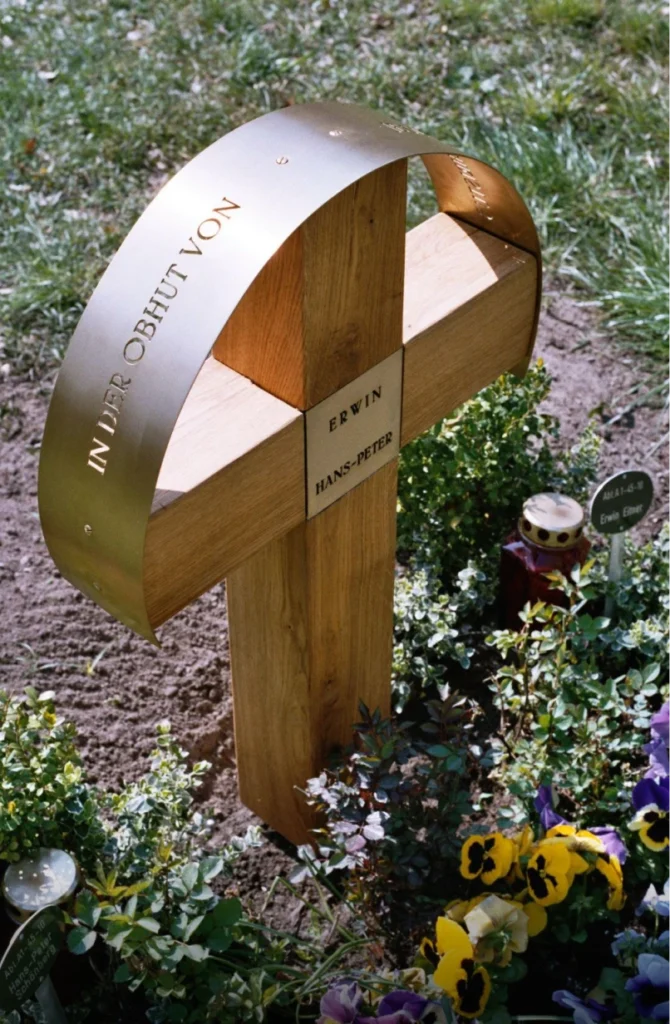 Grabstein mit Kreuz und Messingbogen aus linker Perspektive