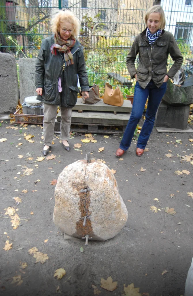 Zwei Angehörige stehen vor einem Grabstein und betrachten ihn gemeinsam