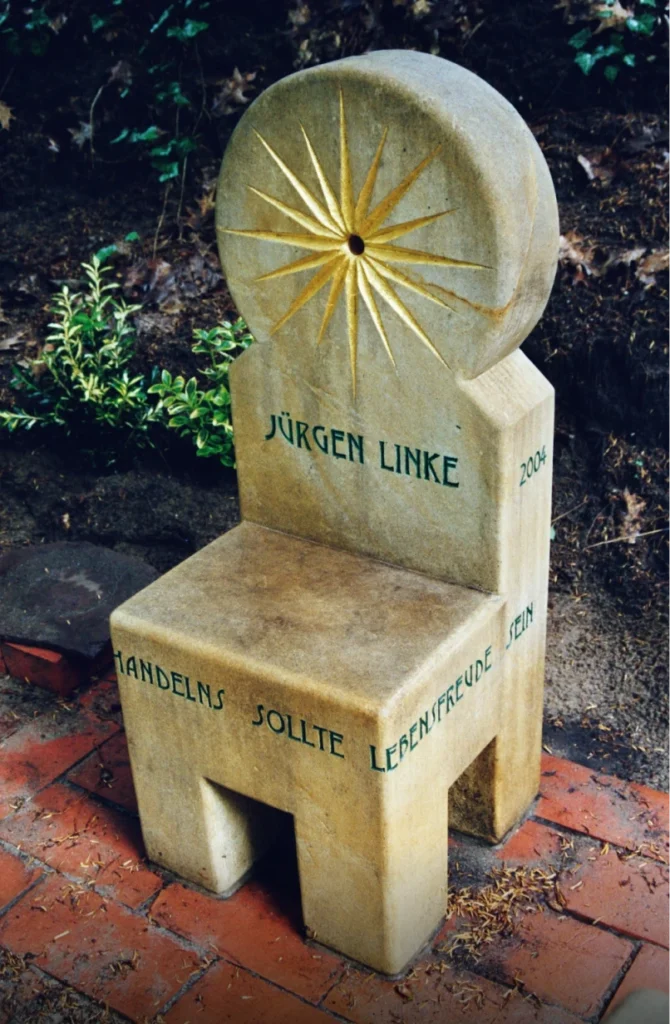 Sandstein-Stuhl mit Inschrift „Leitschnur Eures Handelns sollte Lebensfreude sein“ – Grabmal Jürgen Linke