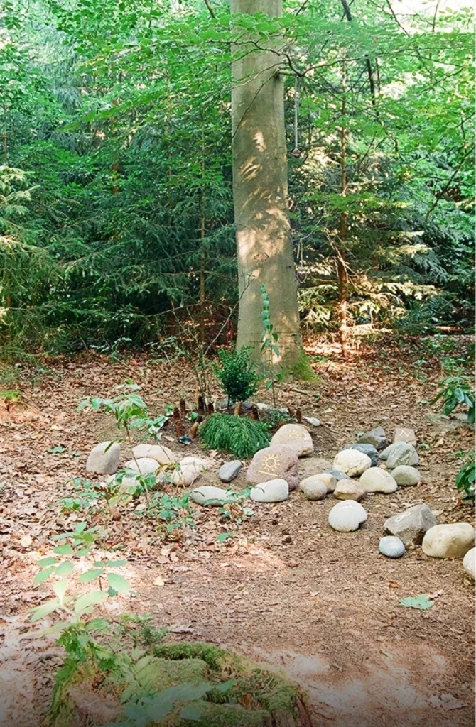 Lose verteilte Findlinge mit einzelnen Buchstaben und Symbolen auf einer Grabfläch