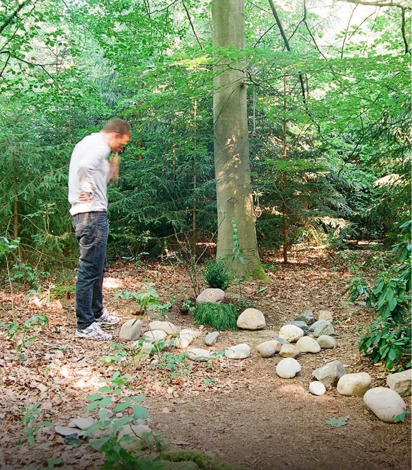 Person betrachtet lose liegende beschriftete Steine eines Grabmals