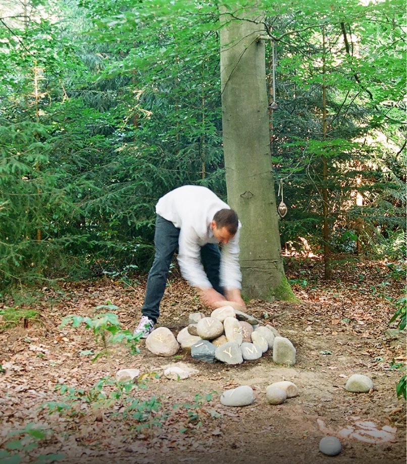 Person legt einen weiteren beschrifteten Stein auf einen Haufen von Findlingen