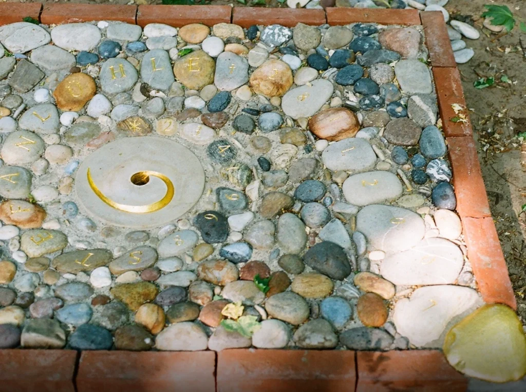 Vergoldeter Bassschlüssel in einem Stein mit Loch als Teil eines Grabreliefs