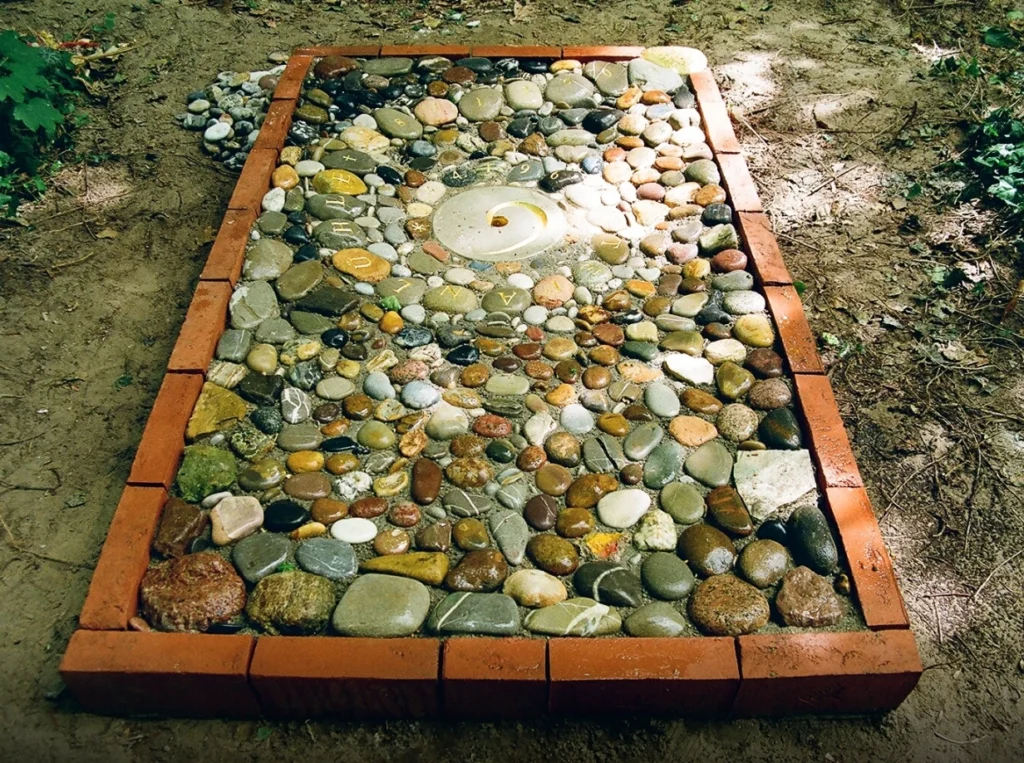 Detail eines Bodenreliefs mit Natursteinen und spiralförmig angeordnetem Schriftzug