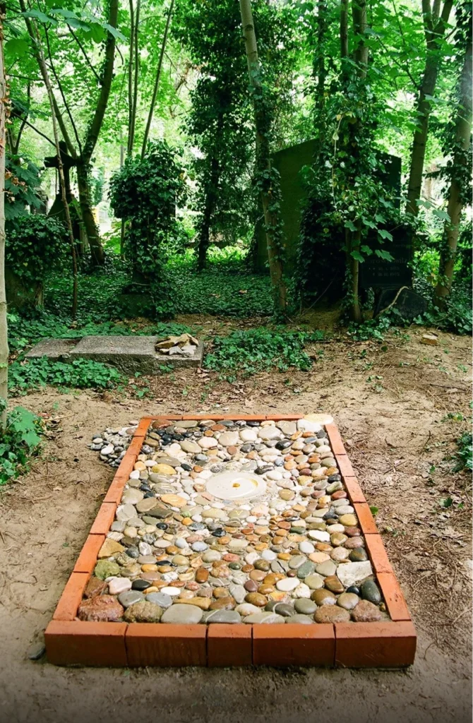 Bodenrelief aus Natursteinen mit Bassschlüssel-Form und spiralförmigem Namensverlauf – Grabmal Stefan Lühle