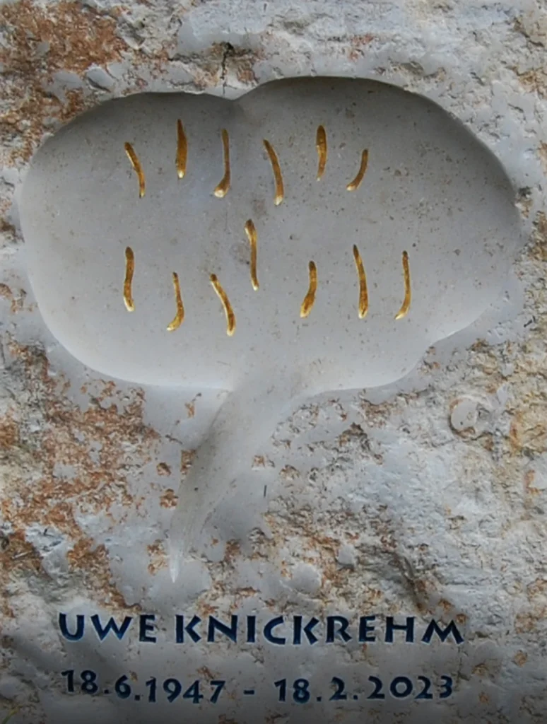 Detail einer Sprechblase mit vergoldeten abstrakten Zeichen auf Grabstein