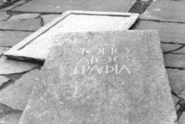 Ausgehöhlte Granit-Gehwegplatte mit der Inschrift „ΤΟΠΟΛΙΟΟΓΑΦΙΑ“ als Depot des Kunstprojekts „ge(h)steine – topolithografia“ von Michael Spengler