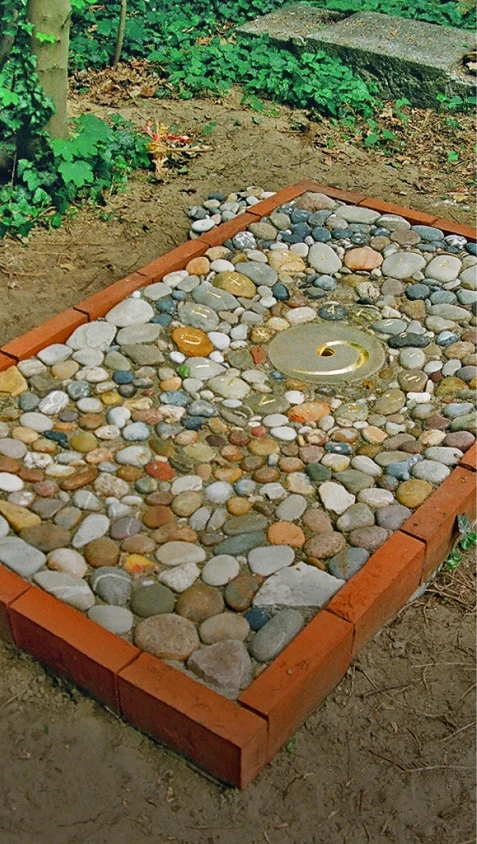Grabstelle mit Bodenrelief aus vielen Steinen und spiralförmiger Gestaltung – Denkwerk Stefan Lühle
