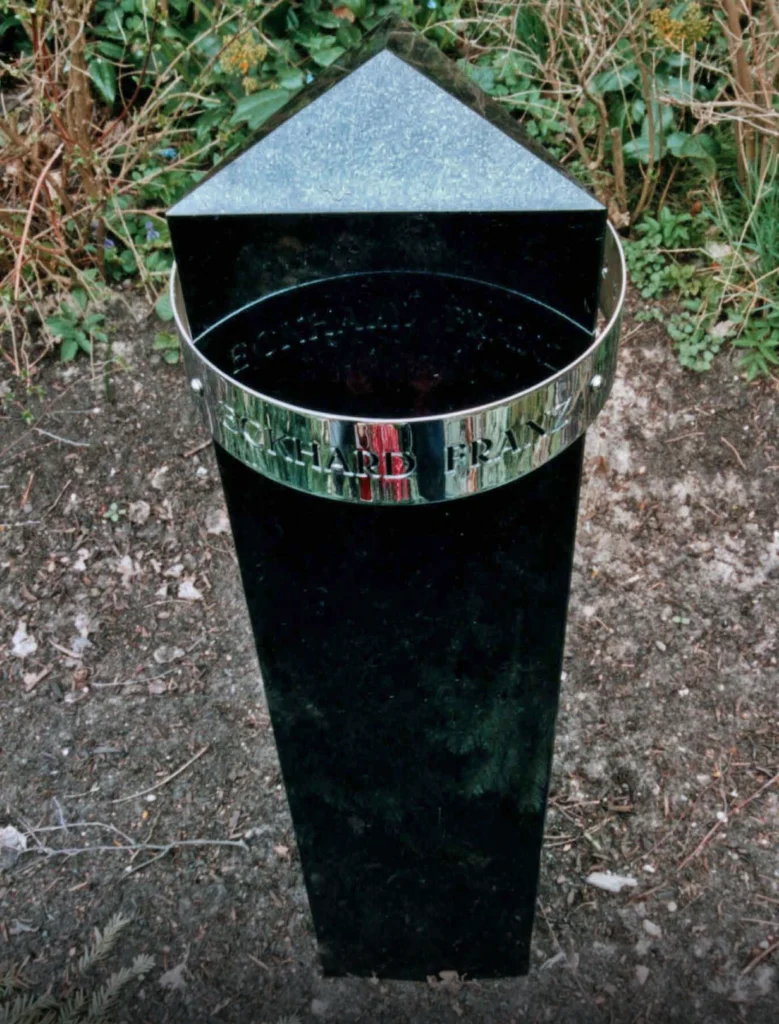 Schwarzer Granitgrabstein mit dreieckigem Querschnitt und pyramidenförmigem Abschluss