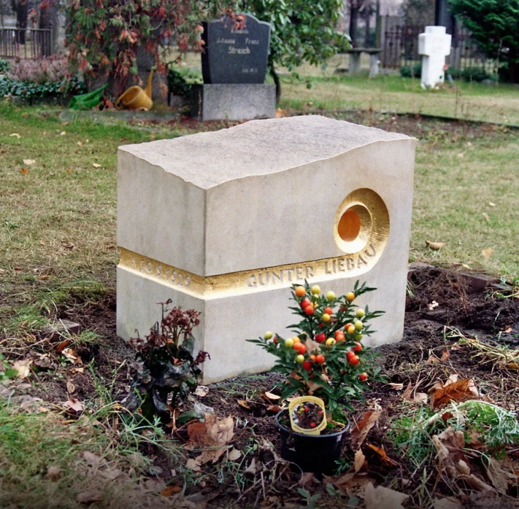 Flach liegender Sandstein mit spiralförmigem, vergoldetem Durchbruch – Grabmal für Günter Liebau