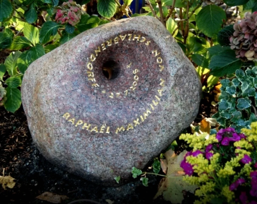 Grabstein aus rötlichem Findling mit trichterförmigem Durchbruch – Denkwerk für Raphaël von Michael Spengler