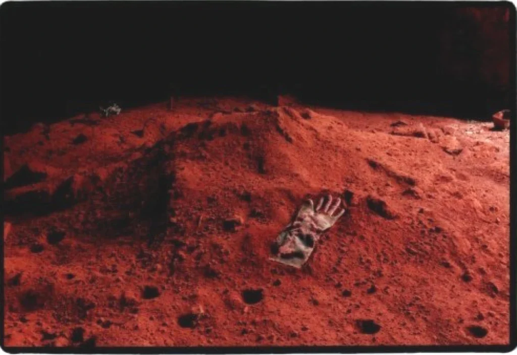 Handschuh liegt auf einem farbigen Pigmenthaufen in einer verlassenen Fabrikhalle in Turin.