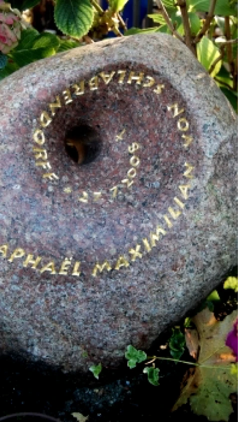 Grabstein aus rötlichem Findling mit trichterförmigem Durchbruch – Denkwerk für Raphaël von Michael Spengler