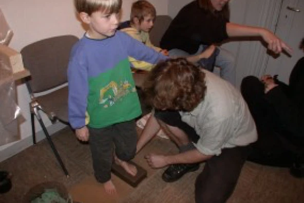 Kind tritt unter Anleitung in feuchten Ton für Fußabdruck